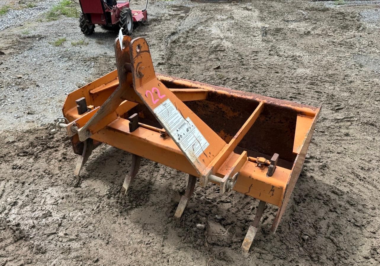 Orange tractor tiller attachment on ground
