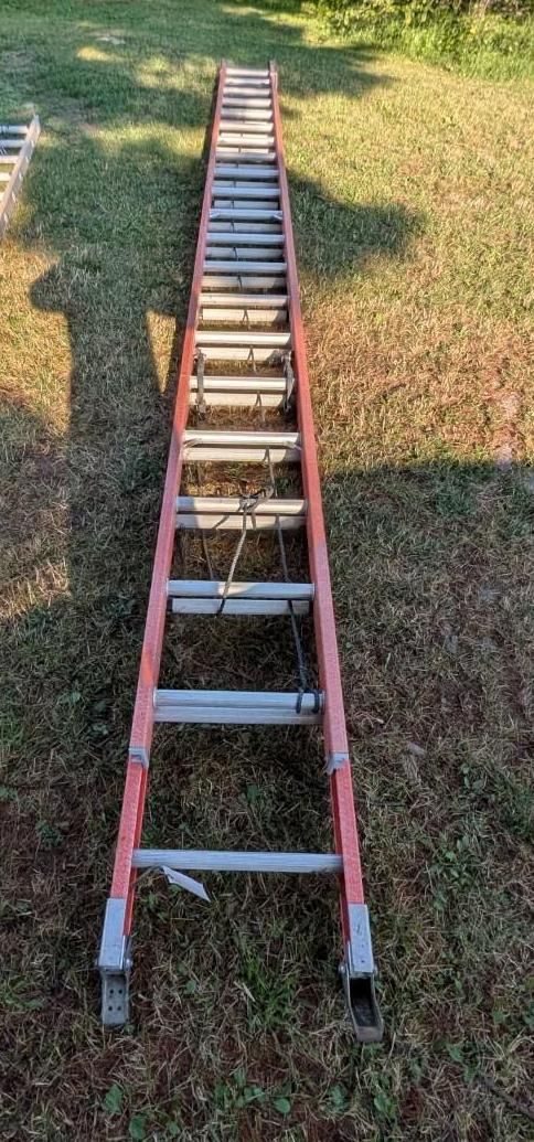 Red extension ladder lying on grass outdoors, viewed from above