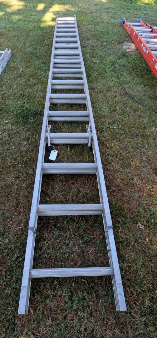 Metal extension ladder lying on grass, viewed from above