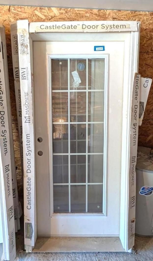 White exterior door with glass panels and narrow side windows in a construction frame, labeled “CastleGate Door System.”