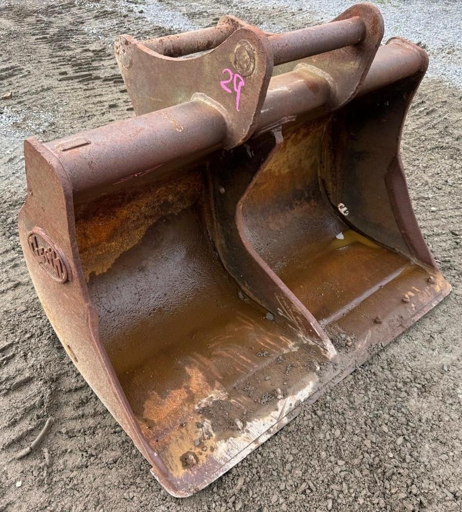 excavator bucket attachment resting on gravel.