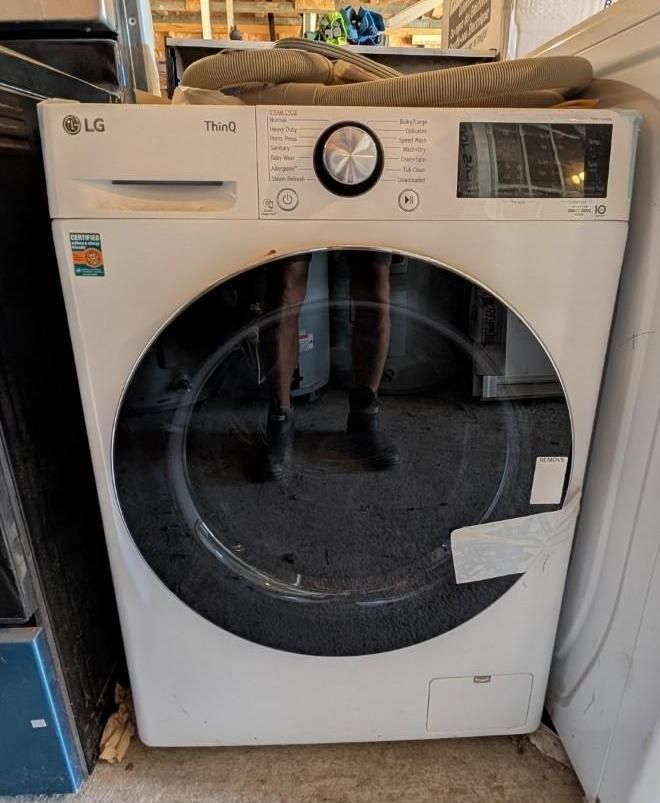 White LG front-load washing machine in a laundry area, with a round door and top control dial.