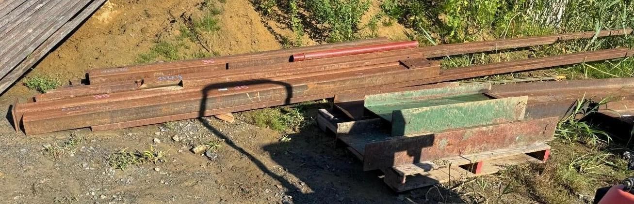 metal rail beam lying on dirt beside stacked bricks in an outdoor work area