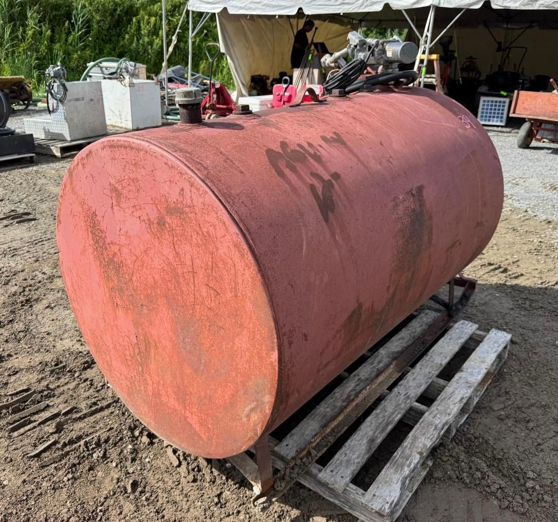 Large red cylindrical tank on wooden pallets in an outdoor yard.