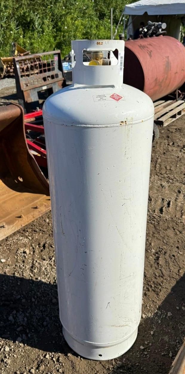 White propane tank standing outdoors on dirt