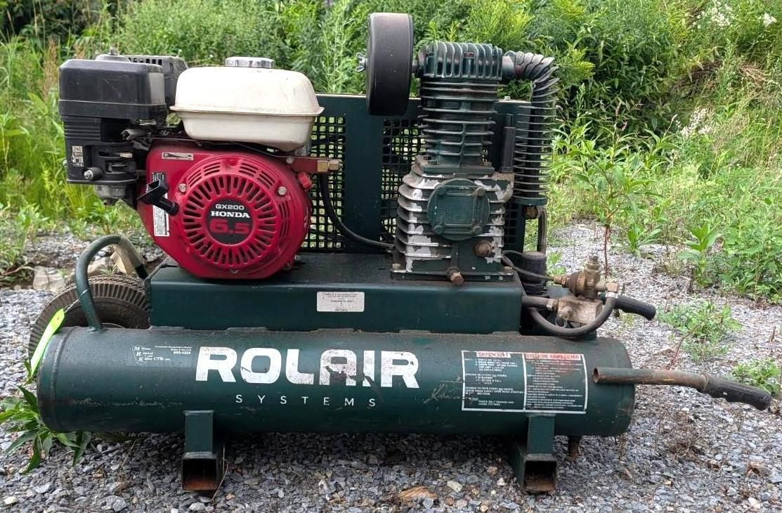 Rolair portable air compressor with red engine, on grassy ground outdoors