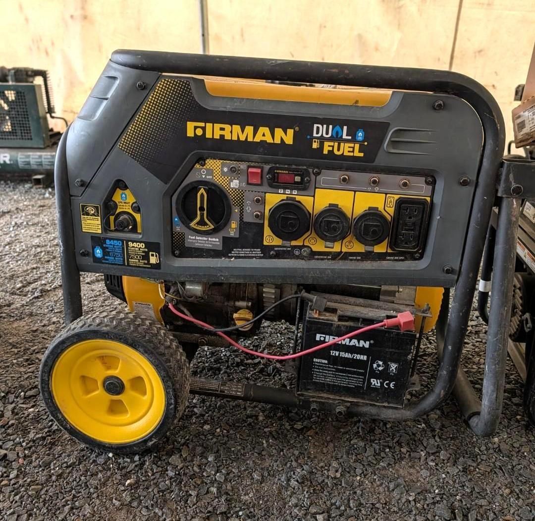 Portable Firman dual-fuel generator with yellow wheels on a gravel surface, shown outdoors near a wall