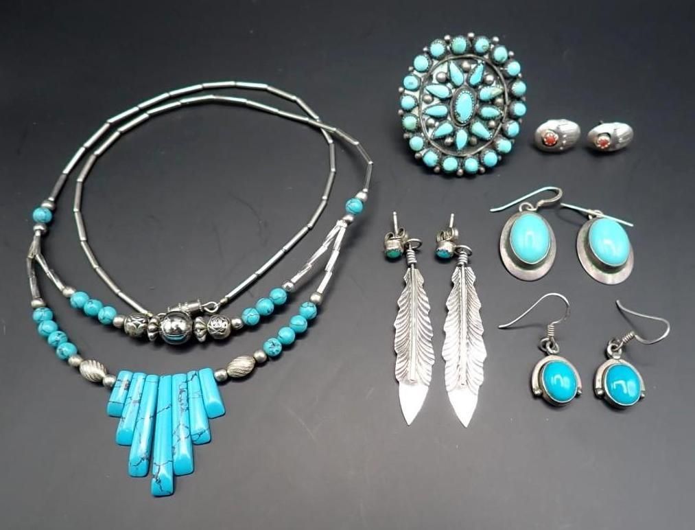Turquoise and silver jewelry set: necklace, brooch, earrings, and rings on a dark background