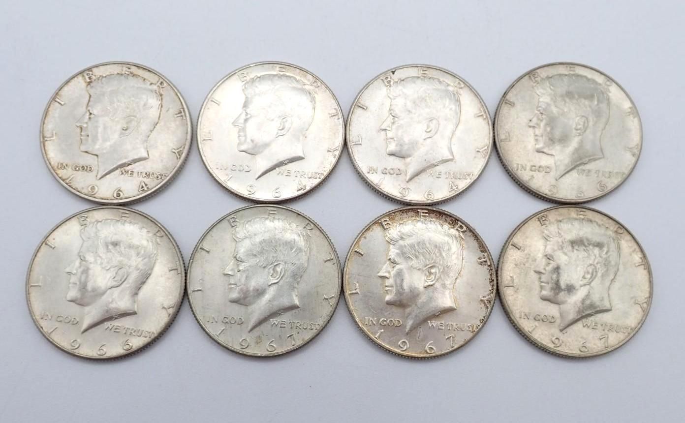 Eight silver-colored coins arranged in two rows on a plain light background.