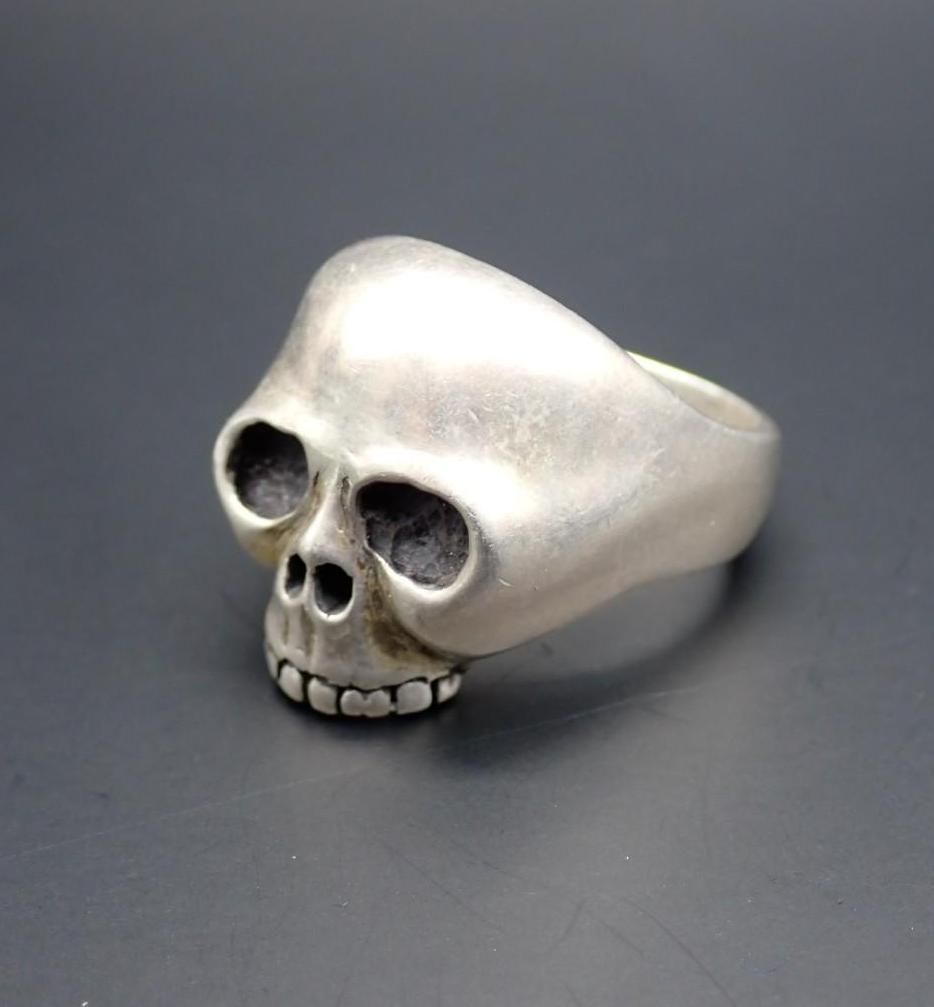 Silver skull-shaped ring on a dark background