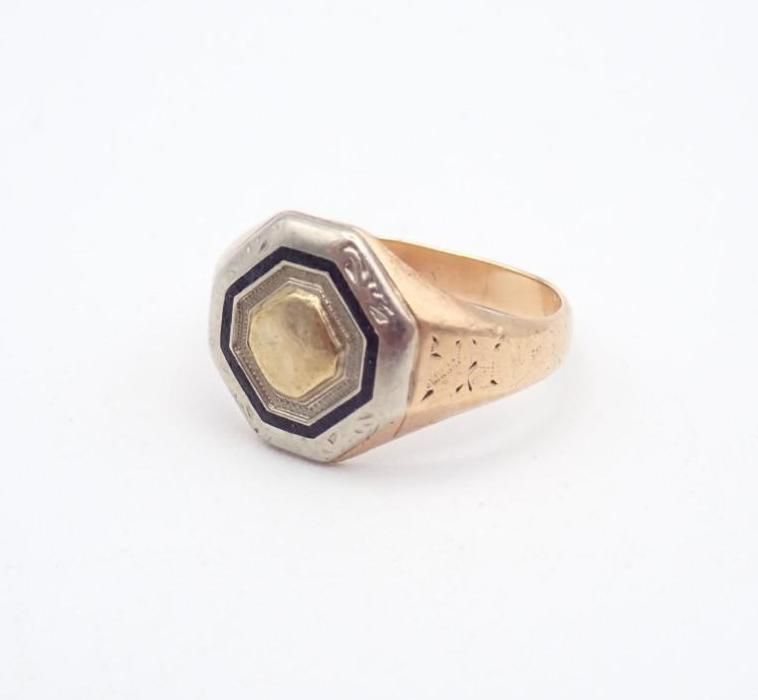 Gold ring with a faceted octagonal black-and-cream bezel on a white background
