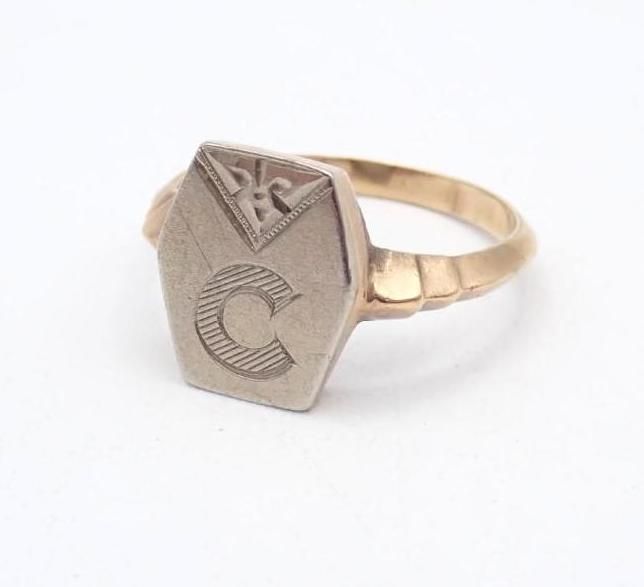 Gold ring with a hexagonal engraved face and letter C on a white background