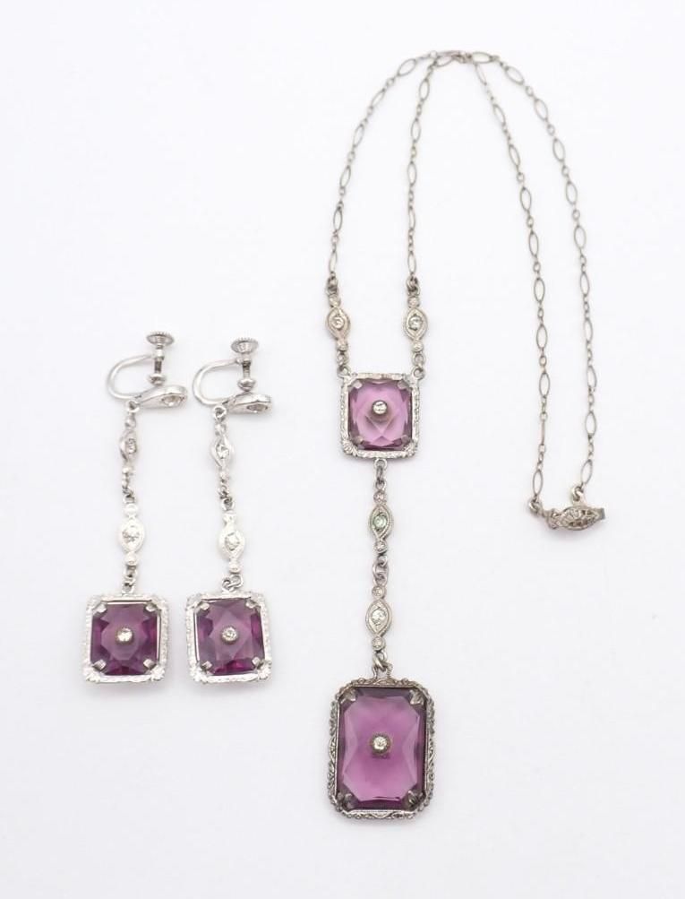 Purple gemstone necklace and matching earrings with silver settings on a white background