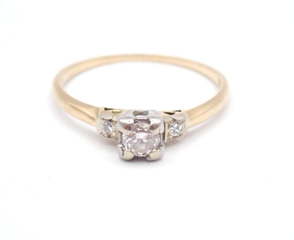 Rose gold ring with a round center gemstone and small side stones on a white background
