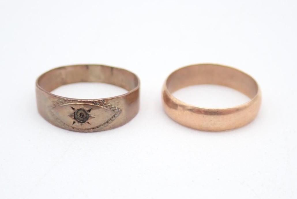 Two gold rings on a white background, one engraved with a small eye design