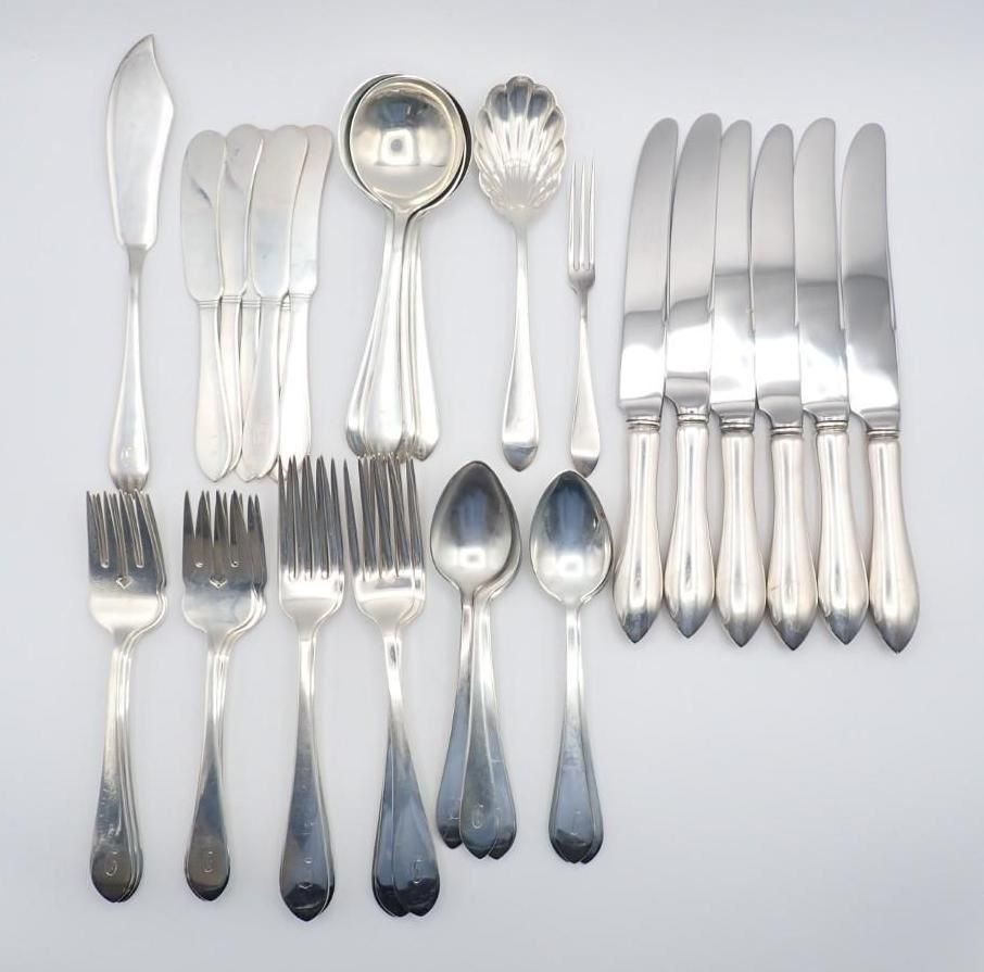 Silverware set arranged on a white background: knives, forks, spoons, and serving utensils.