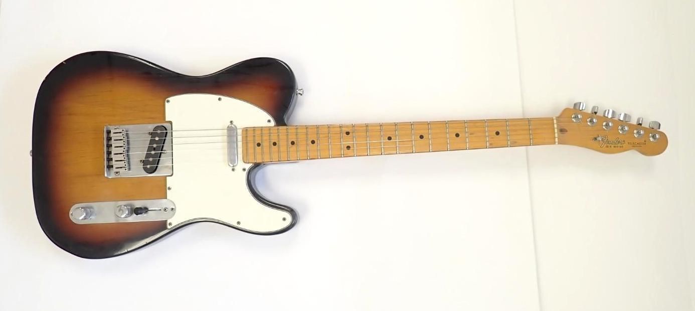 Sunburst electric guitar with white pickguard, lying on a white background
