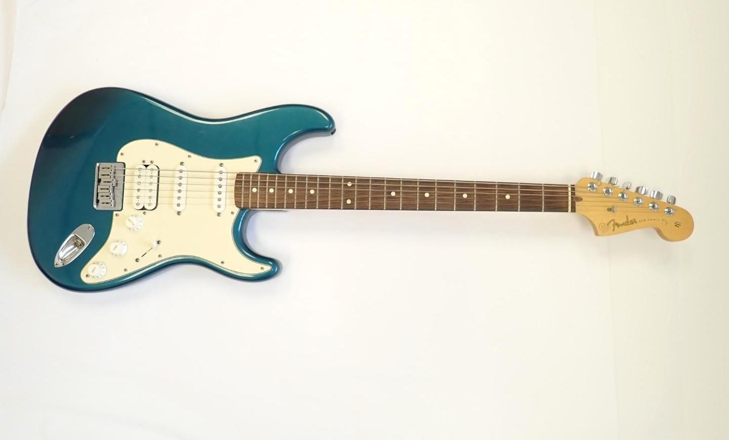 Teal electric guitar with white pickguard on a plain white background