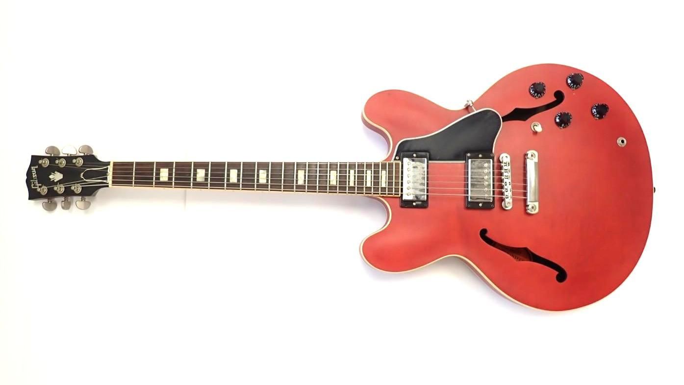 Red semi-hollow electric guitar on a white background, shown horizontally.