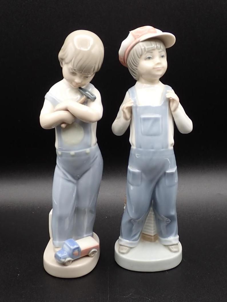 Two porcelain figurines of a child in blue overalls, one facing forward and one turned away.