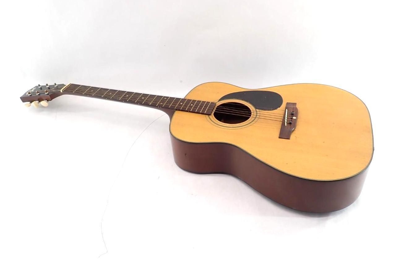 Acoustic guitar with natural wood body and dark neck, lying on a white background
