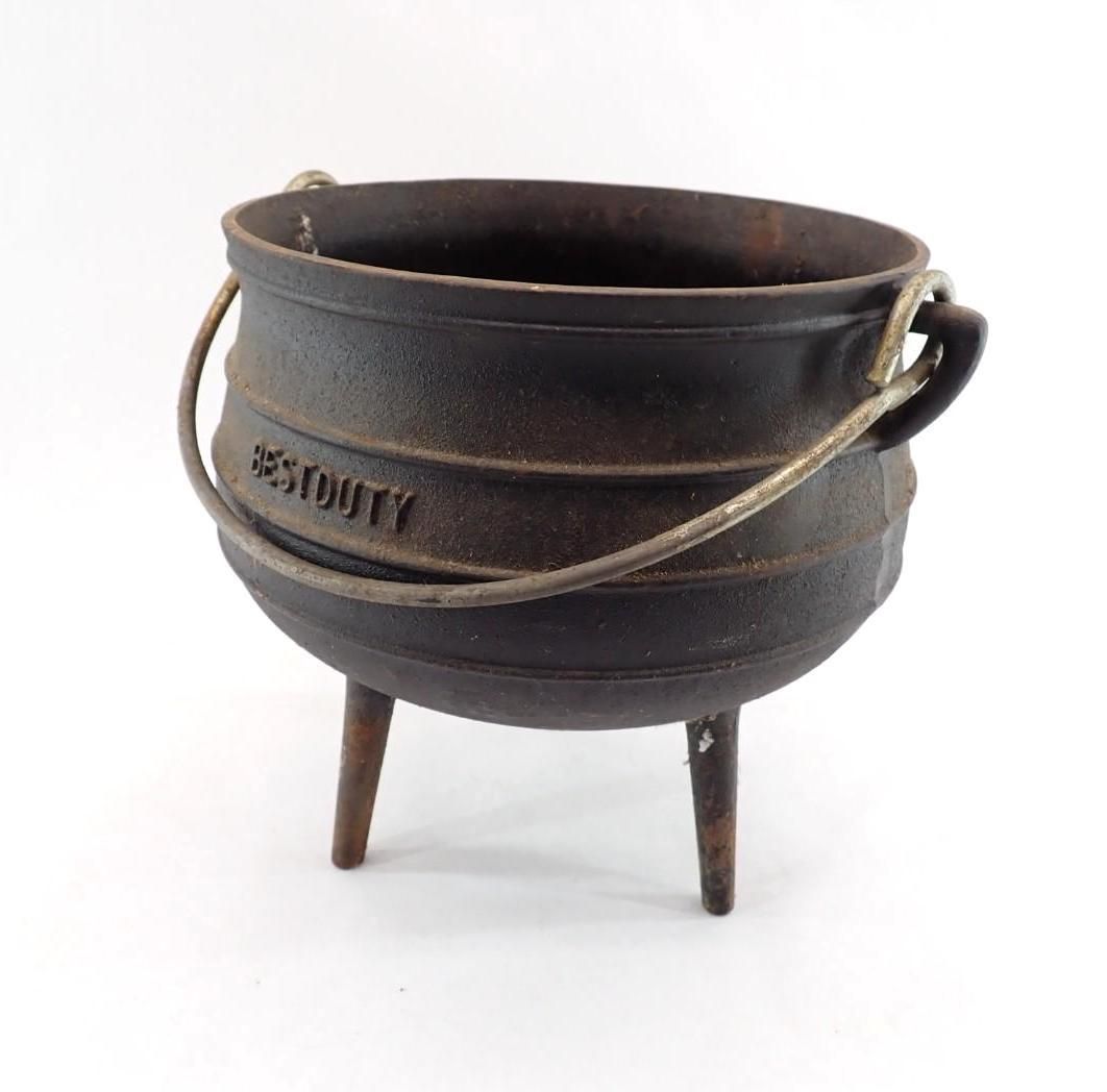 cast-iron cauldron with a metal handle and three legs on a white background