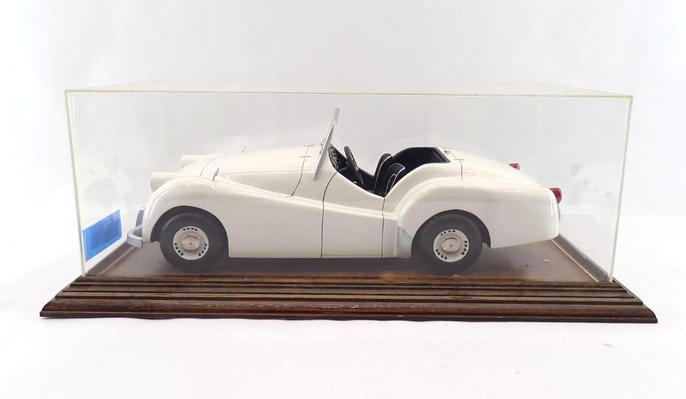 White vintage convertible model car displayed in a clear case on a wooden base