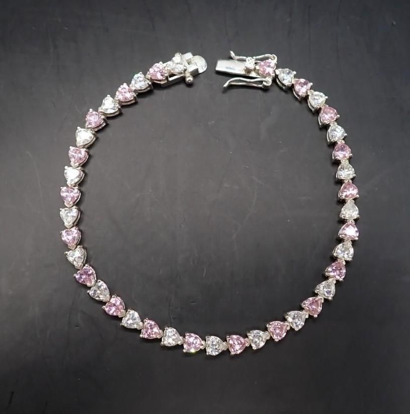 Silver bracelet with pink heart-shaped gemstones on a black background