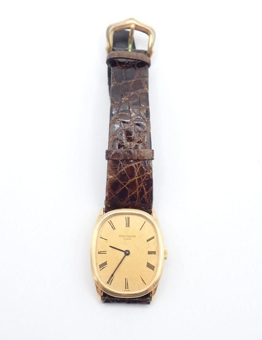 Gold wristwatch with brown leather strap on a white background