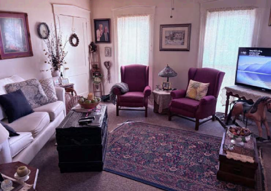 Cozy living room with sofa, two burgundy chairs, rug, side table, and TV on a small table
