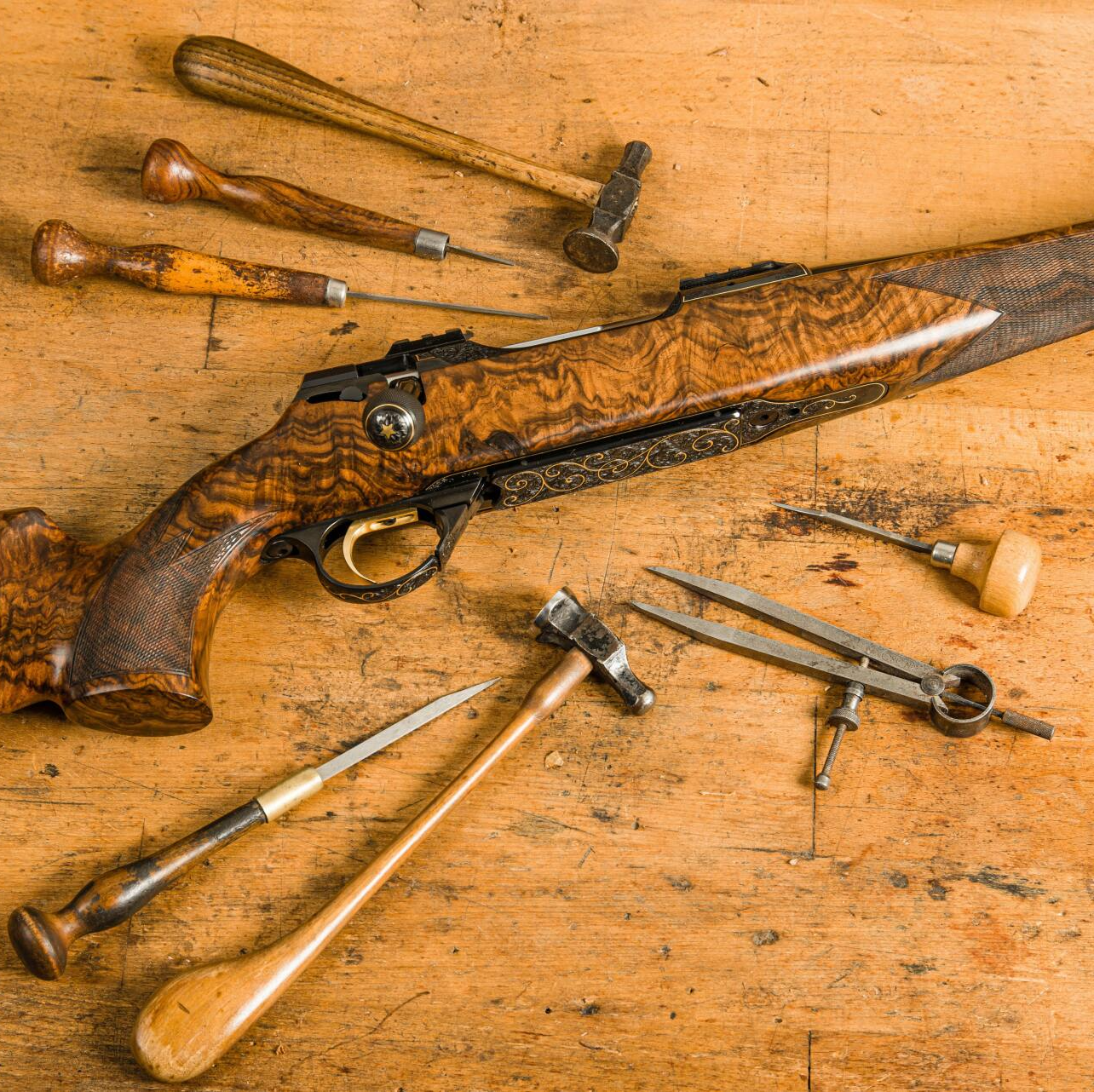 A detailed wooden rifle with tools arranged around it on a wooden surface.