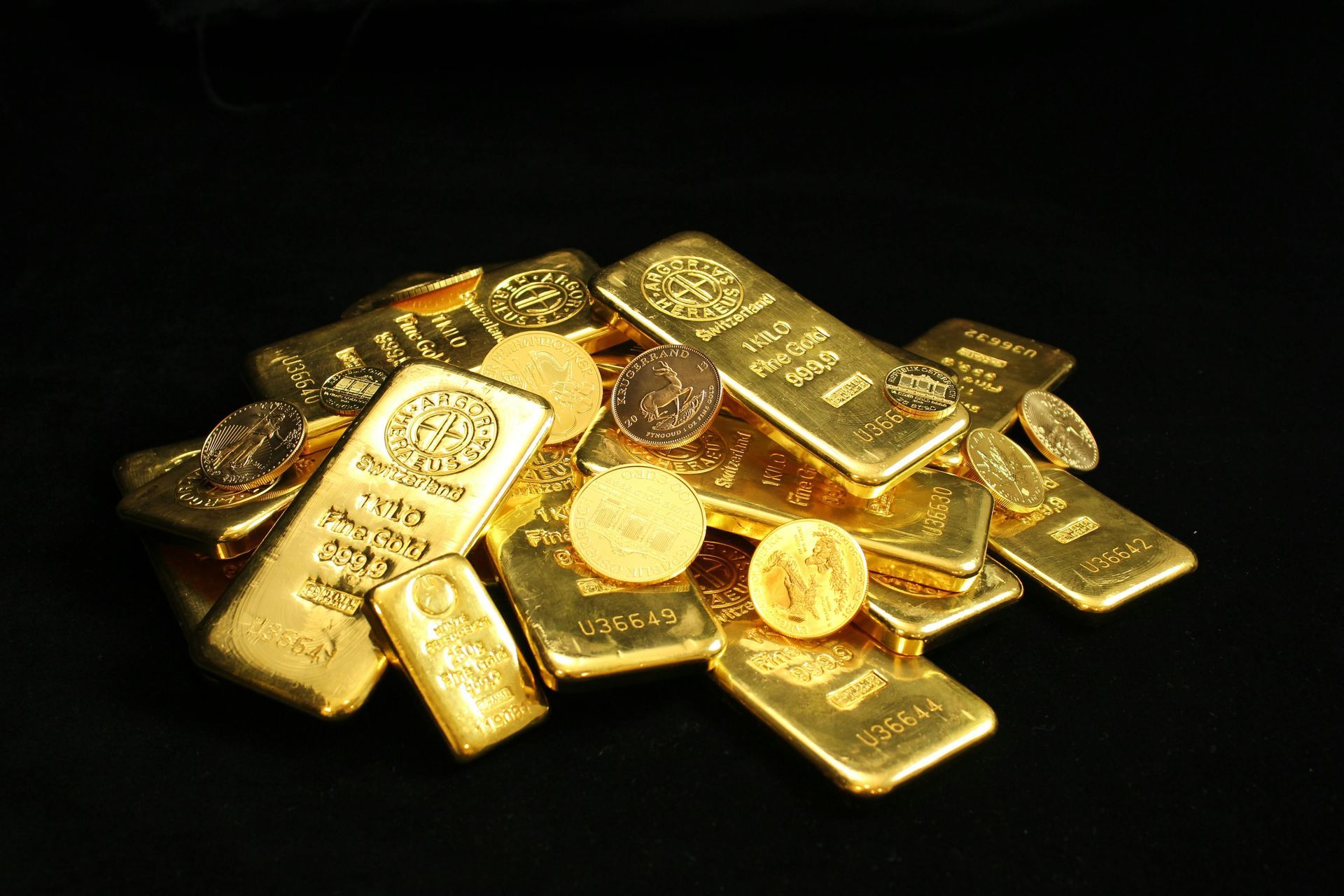Pile of gold bars and coins on a black background