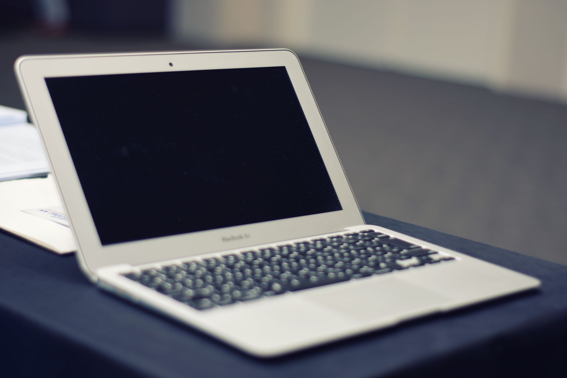 White laptop on a dark table with the screen open and turned off