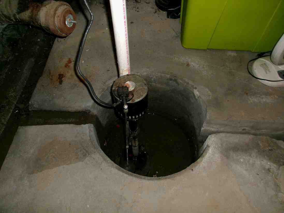 A metal pump handle over a dark circular well opening in a concrete floor