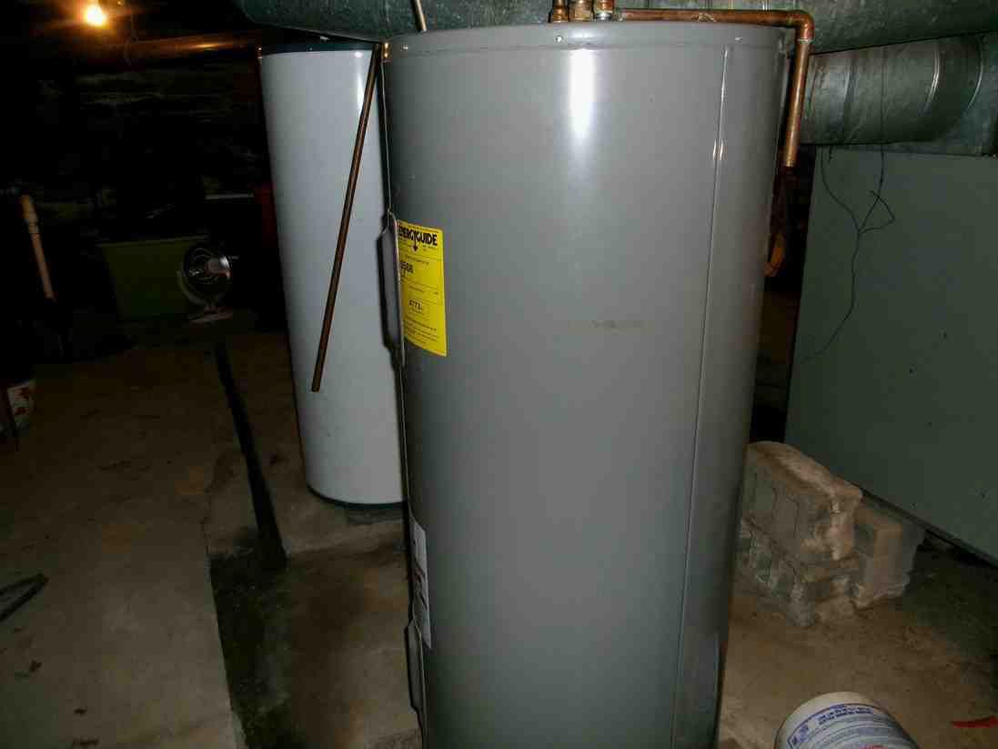 Two large gray water heaters in a basement utility room