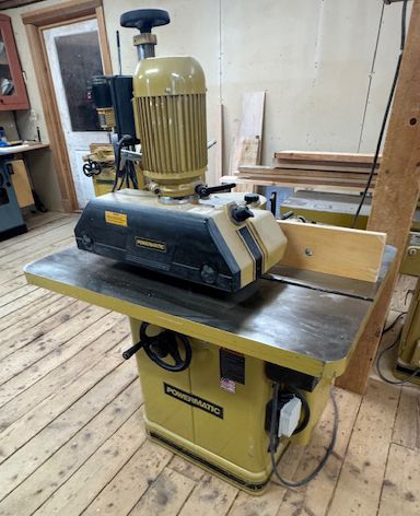 Yellow woodworking planer in a workshop.