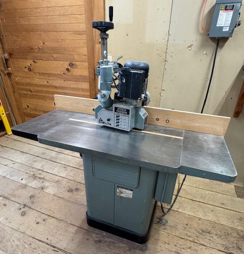 Industrial woodworking shaper with gray table in a workshop.