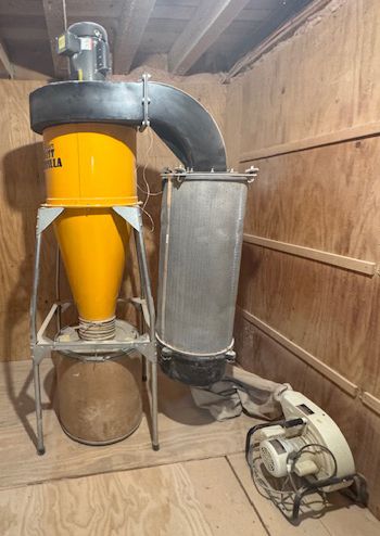 Yellow dust collector and ductwork connected to a blower in a wooden workshop room
