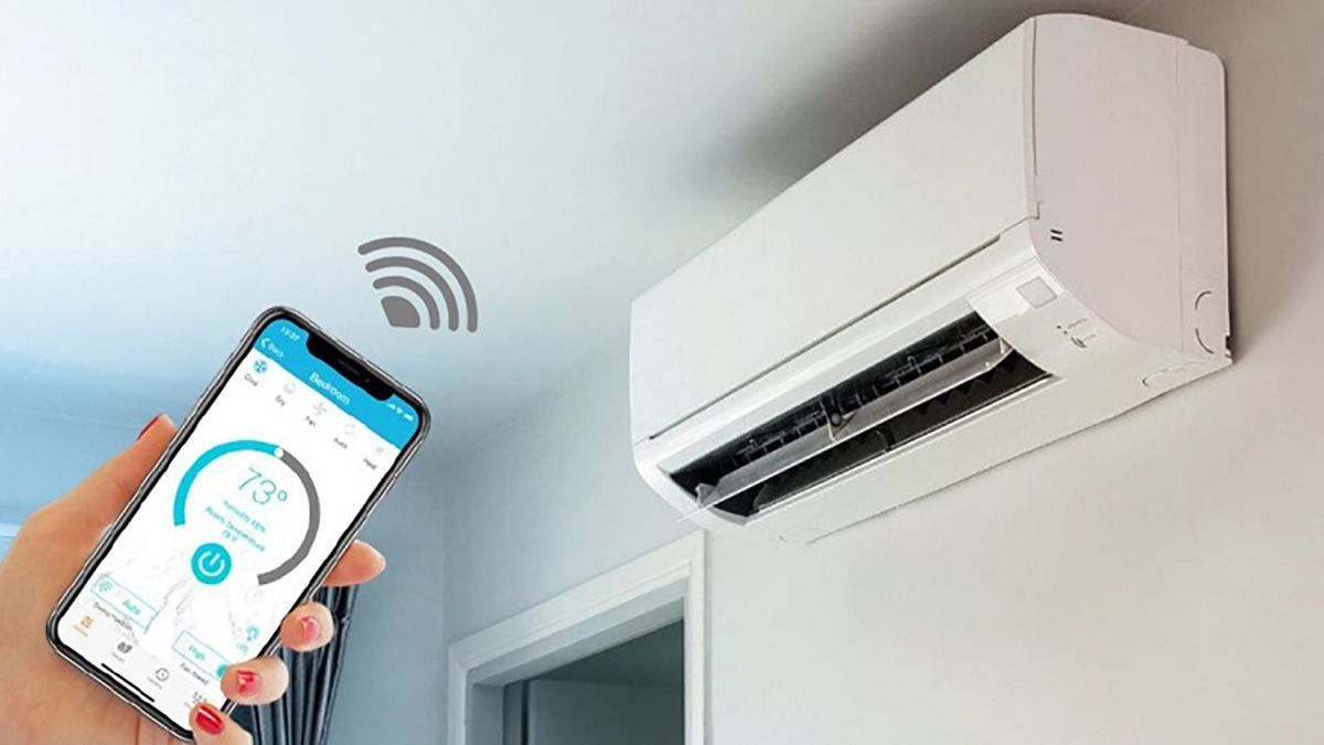 Main utilisant un smartphone pour régler la température d'un climatiseur intelligent. Unité blanche sur un mur blanc.