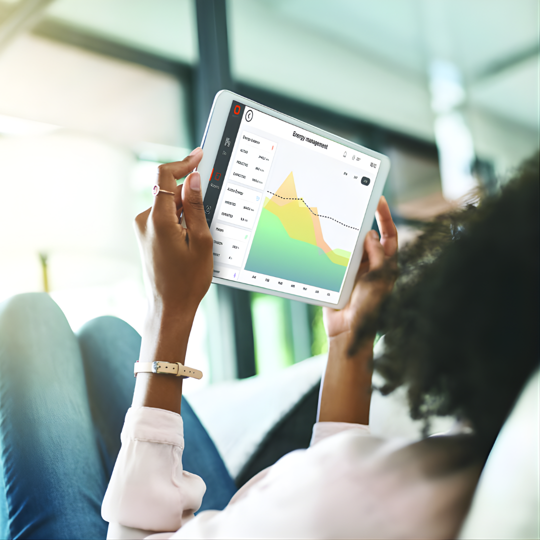 Personne allongée, consultant un graphique sur une tablette. Intérieur baigné de lumière naturelle.