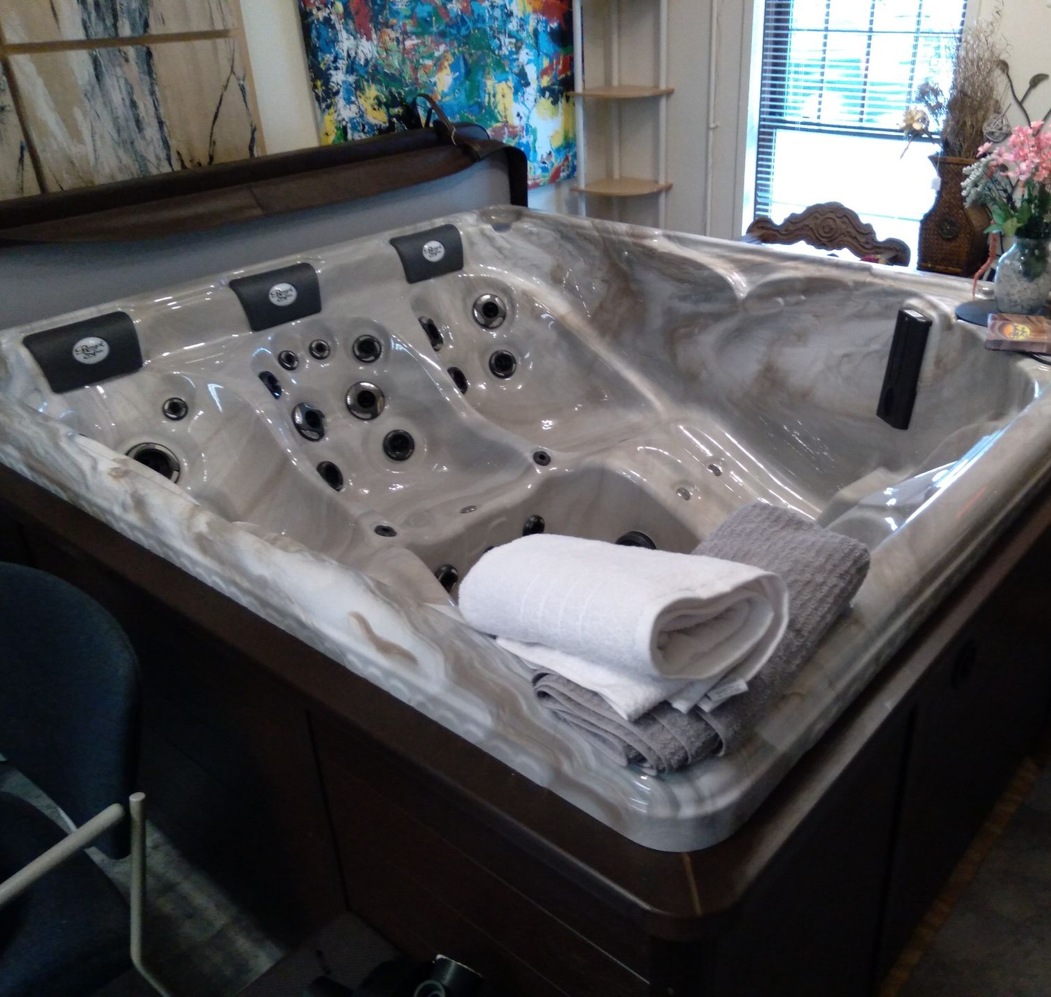 A hot tub is sitting on a tiled patio in front of a brick building.
