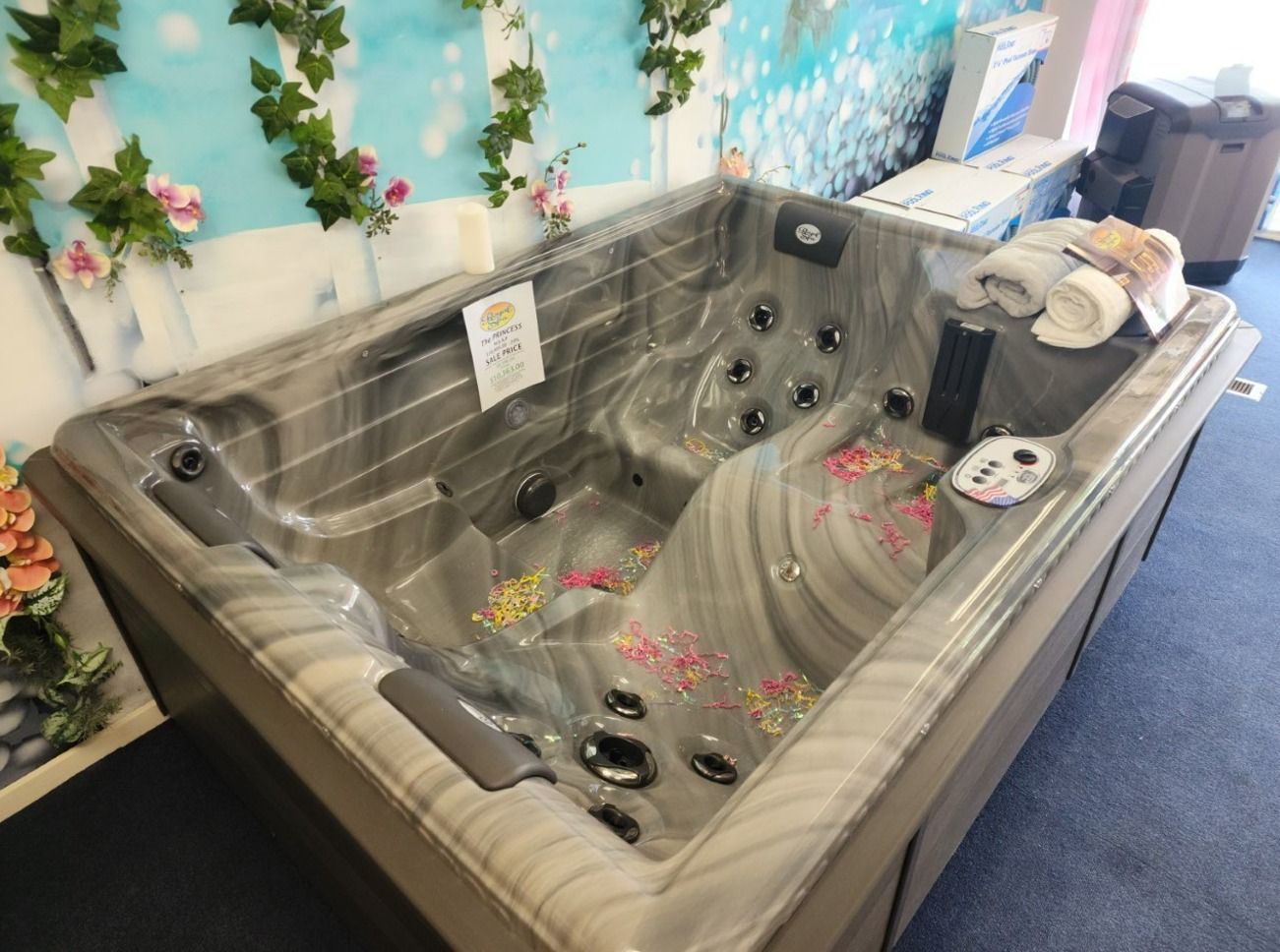 A hot tub is sitting on a tiled patio in front of a brick building.