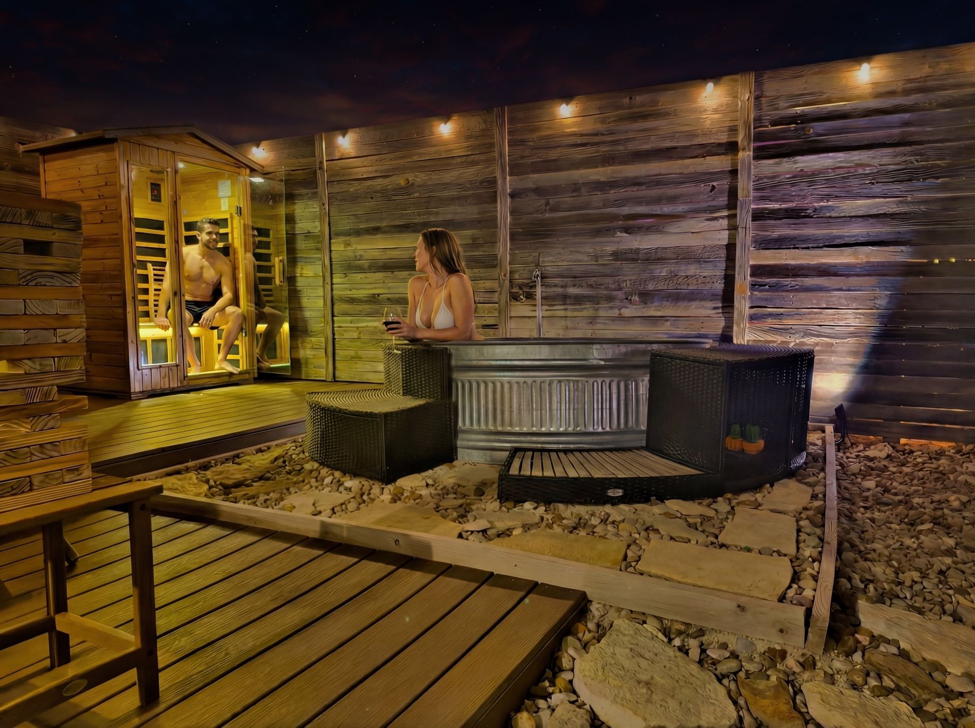 Couple enjoying the private infrared sauna and plunge tub at night in Quiroga's spa yard