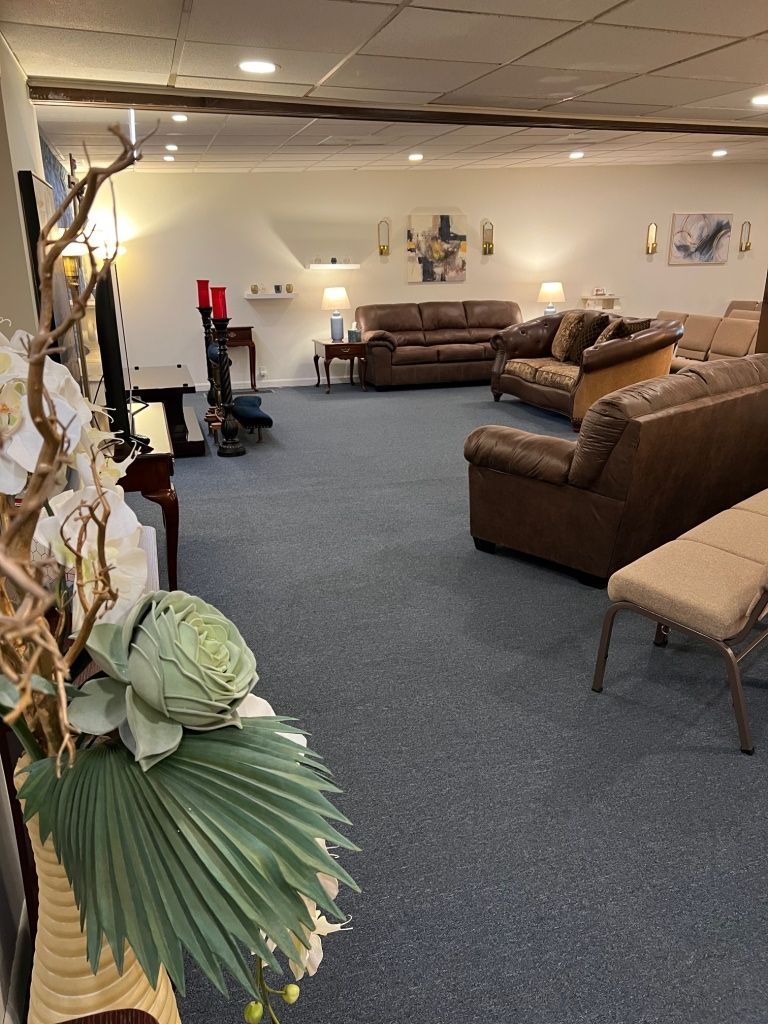 A showroom with multiple brown leather sofas and chairs, blue carpet, and decorative items.