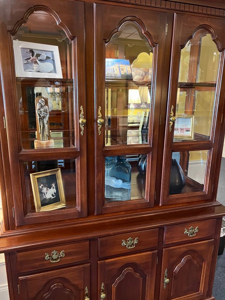 Wooden display cabinet with glass doors, holding various decorative items; gold hardware.