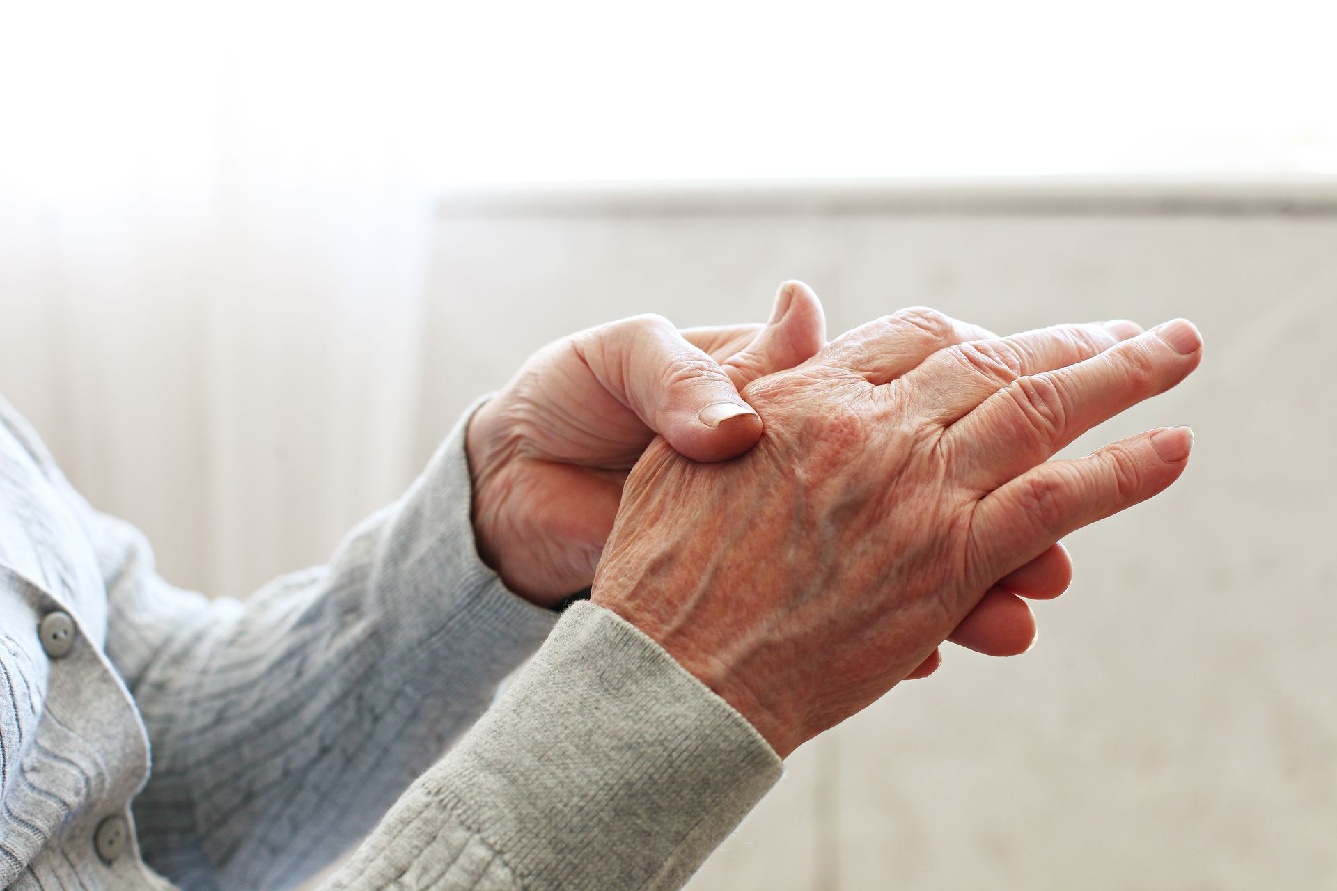 Die Hände einer älteren Person, eine Hand hält und massiert sanft die Knöchel