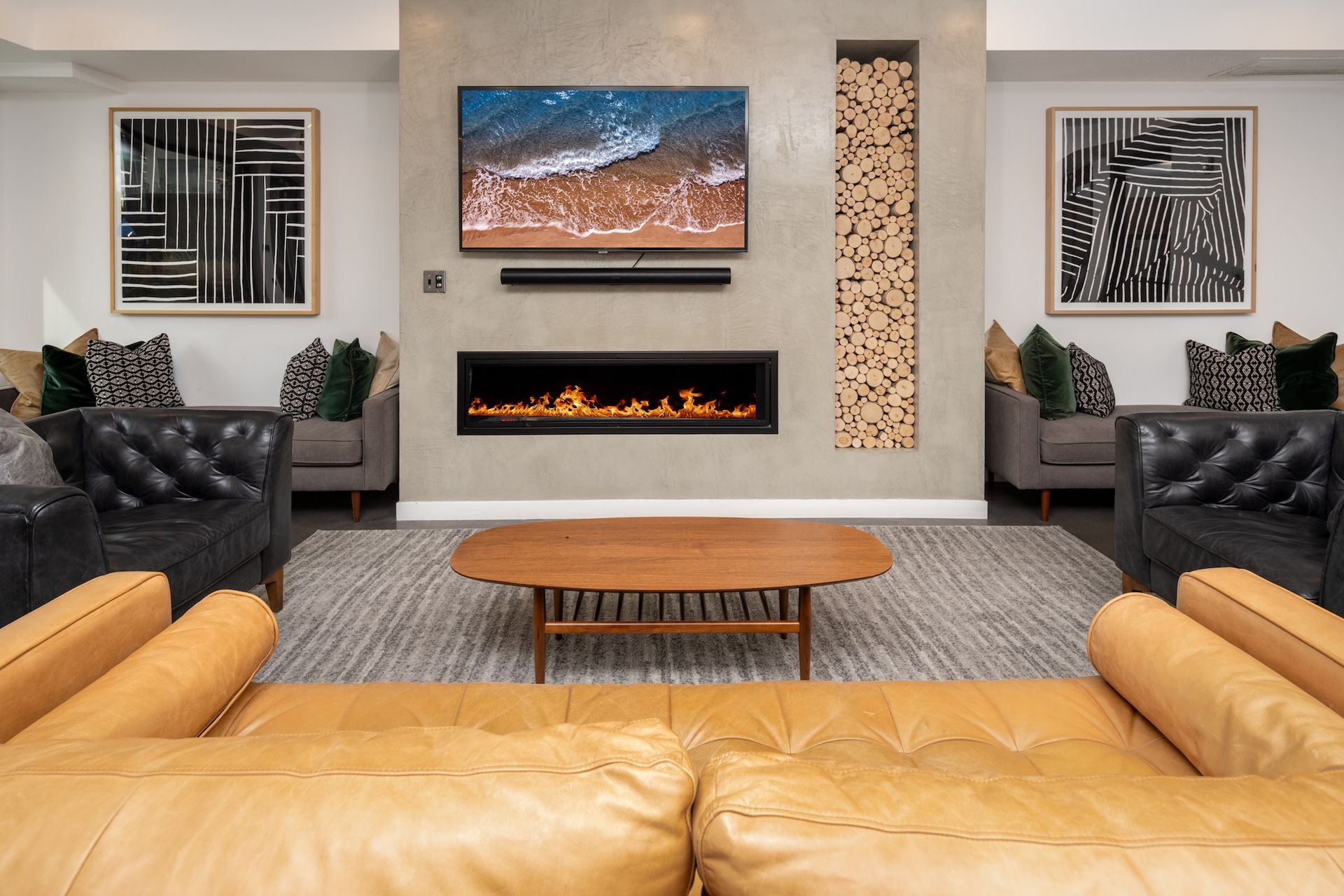 Lounge area with leather couches, fireplace, TV, artwork, and a wooden coffee table.