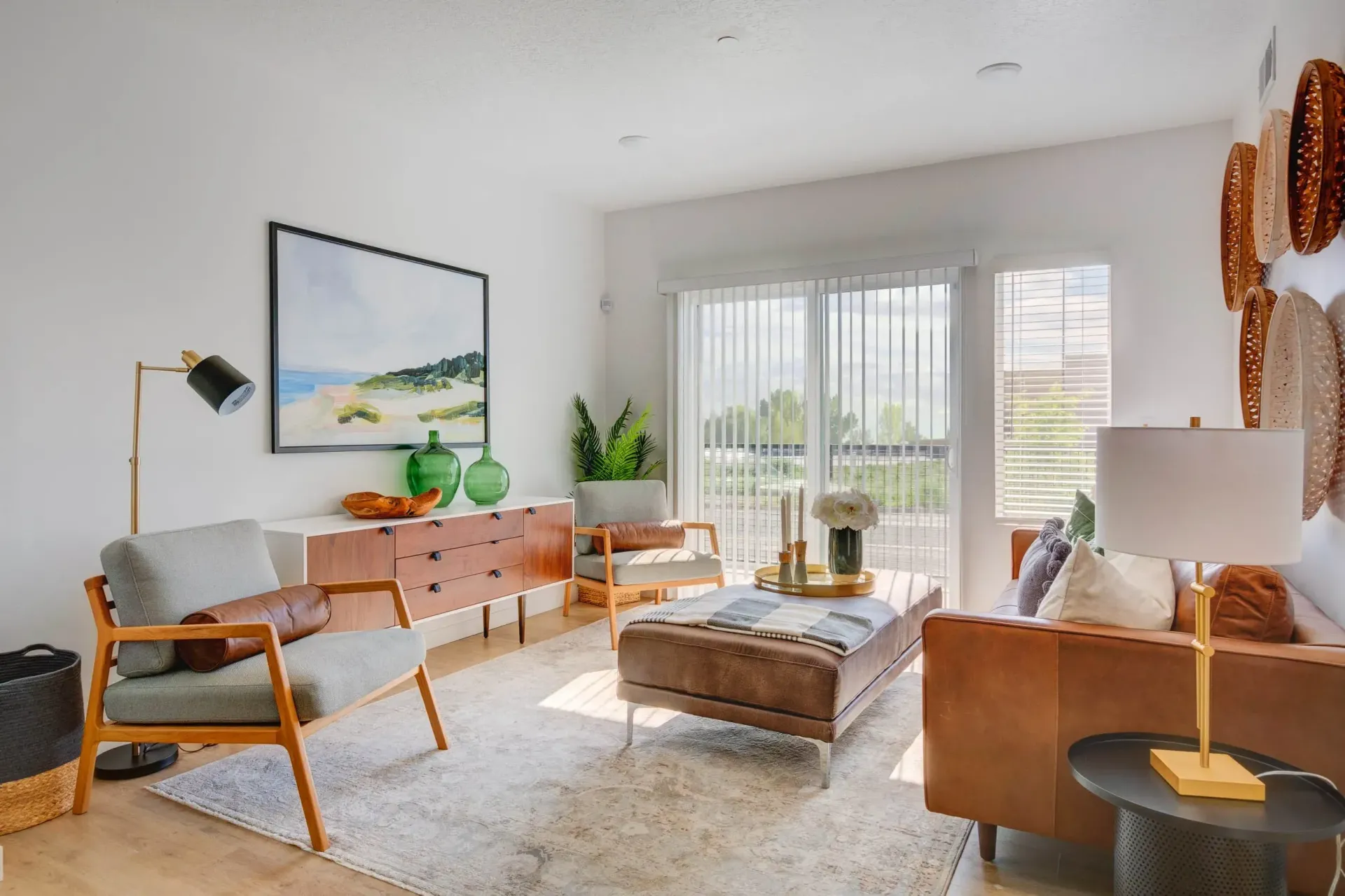 A living room with a couch , chairs , ottoman and a painting on the wall.
