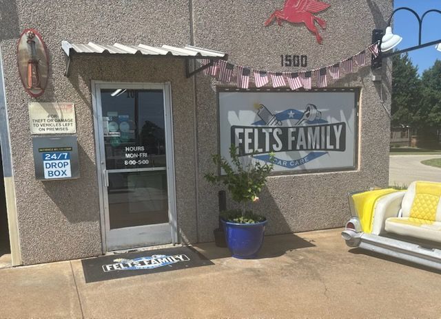 Storefront with glass door, “Felts Family” sign, yellow bench, and potted plant in front.