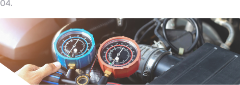 Hand holding blue and red gauge dials near a car engine